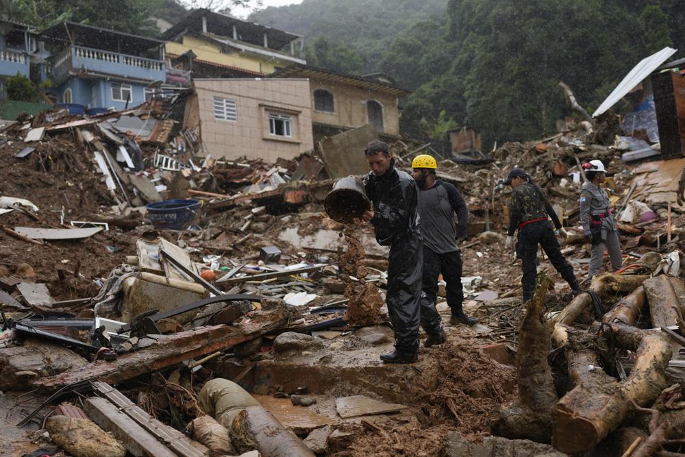 Rescue workers stands on the destruction of a mudslide on the third day of search efforts for victims in Petropolis, Brazil, Friday, Feb. 18, 2022. (AP Photo/Silvia Izquierdo)